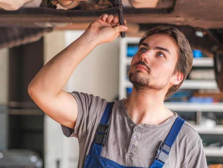 Kfz-Mechaniker kontrolliert den Unterboden eines Autos. Kfz-Mechaniker kontrolliert den Unterboden eines Autos.