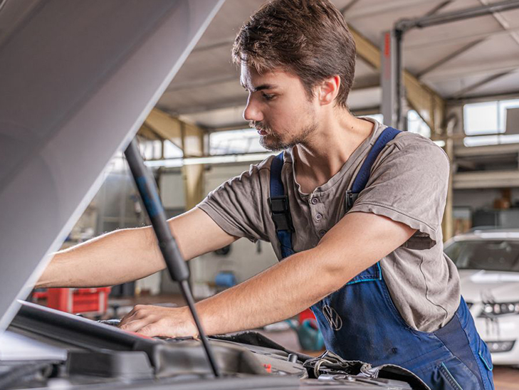 Kfz-Mechaniker steht vor offener Motorhaube. Kfz-Mechaniker steht vor offener Motorhaube.