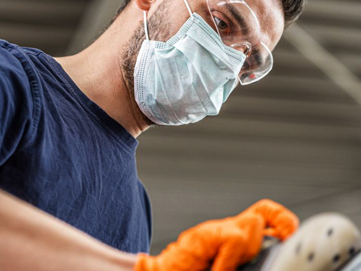 Werkstattmitarbeiter mit Schutzbrille und Maske beim Polieren eines Autos. Werkstattmitarbeiter mit Schutzbrille und Maske beim Polieren eines Autos.