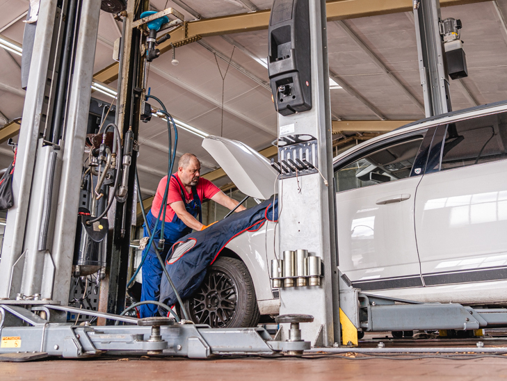 Kfz-Mechaniker führt Reparatur am Motorraum durch. Kfz-Mechaniker führt Reparatur am Motorraum durch.